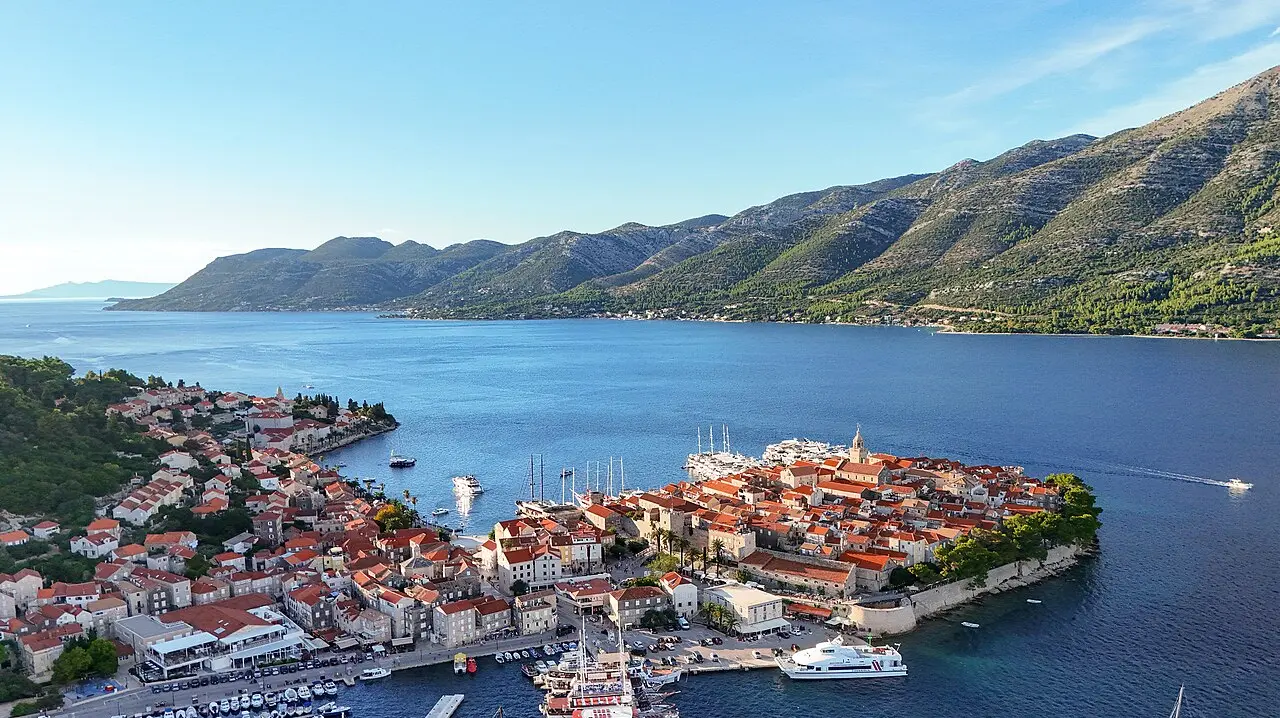 Aerial view of the walled old town of Korčula on its small peninsula jutting into the blue Adriatic, with terracotta rooftops and towers