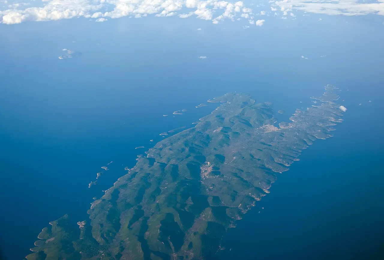 Green wooded hills and the coastline of Korčula island seen from above, with the blue sea beyond