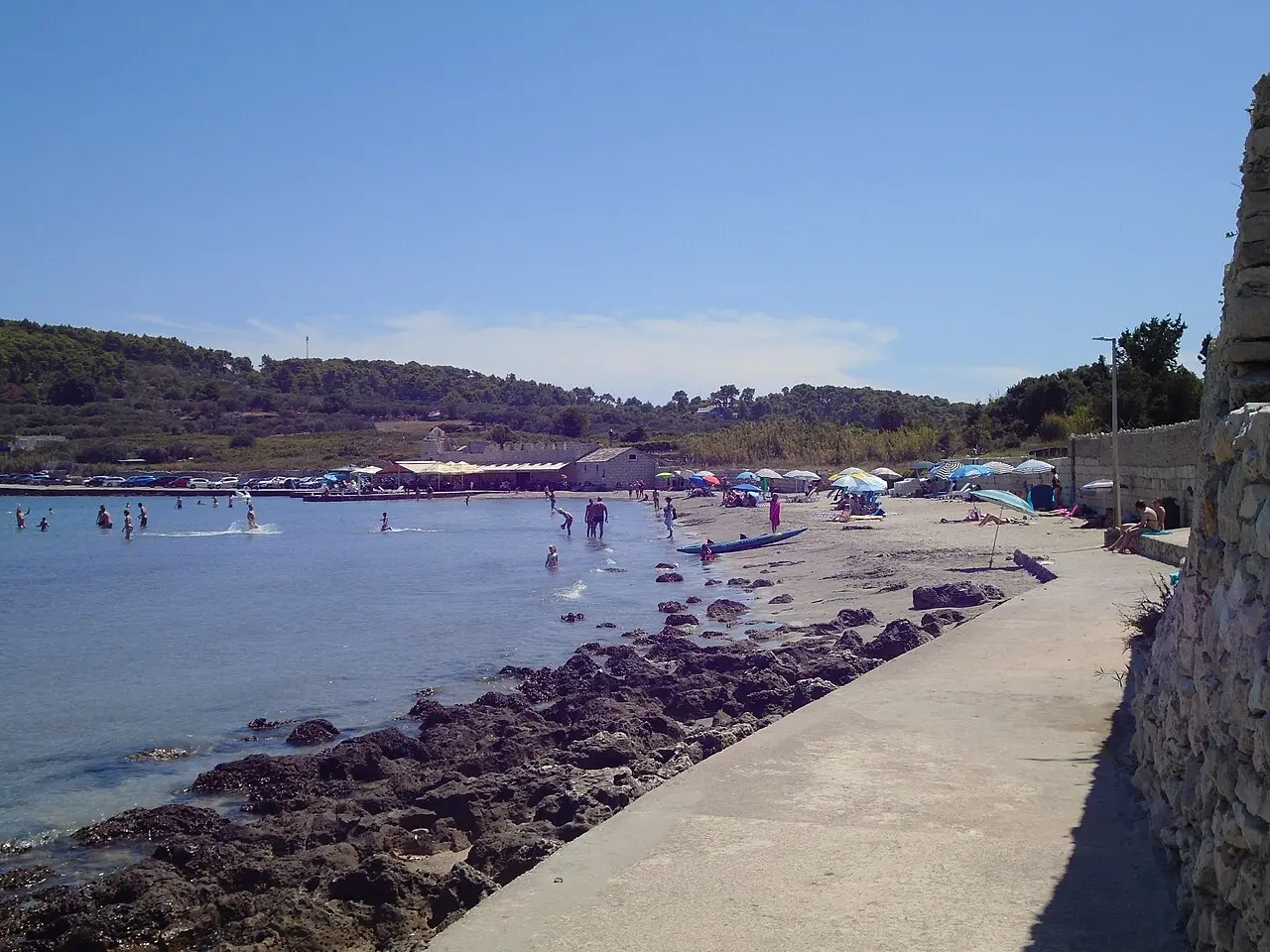 The shallow sandy beach of Bilin Žal at Lumbarda on Korčula, with clear turquoise water and low rocks