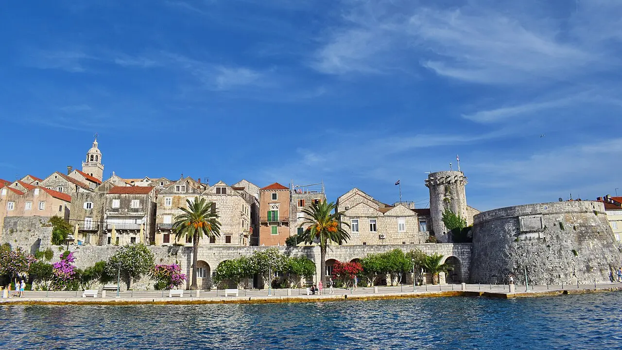The old town of Korčula on its peninsula seen from a distance across the Adriatic, backed by wooded hills