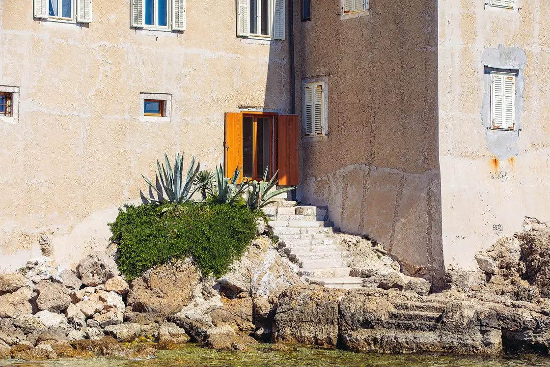 A doorway and stone steps leading straight down to the sea in Krk old town