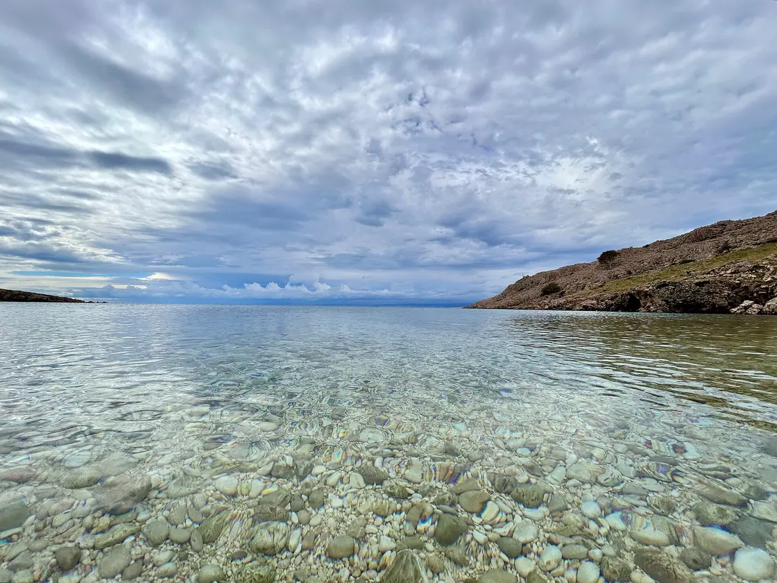 Clear shallow water over pebbles in Surbova cove near Stara Baska on Krk