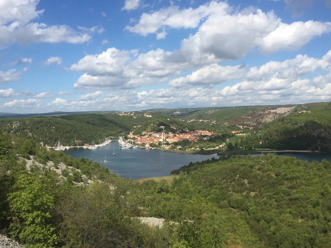 The Krka river widening into a green estuary between wooded hills