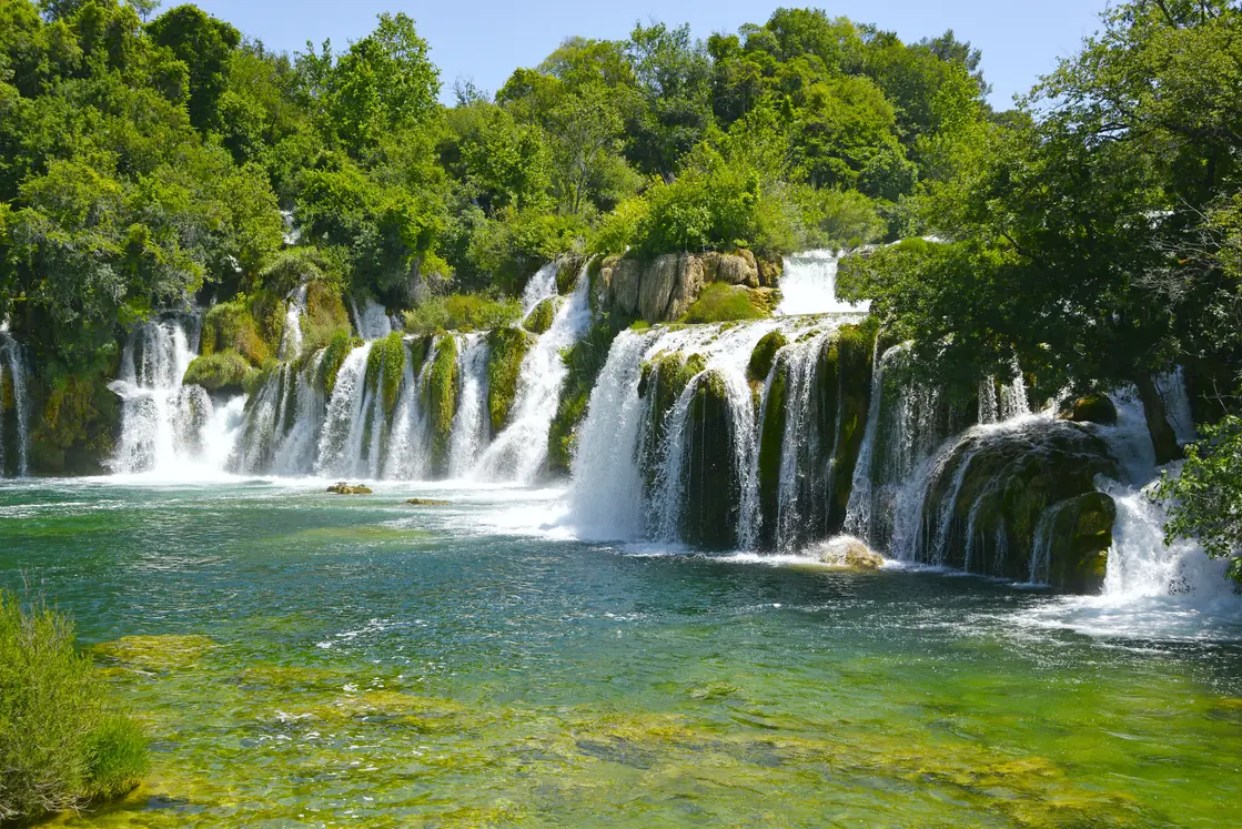 The full width of the Skradinski Buk waterfalls spilling through green forest