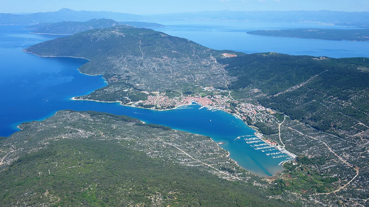Aerial view of the long green northern spine of Cres island in the Kvarner bay, looking north over limestone hills and inlets
