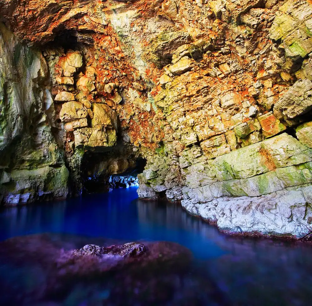 The rocky opening of Odysseus Cave on the south coast of Mljet, with deep blue sea water inside the collapsed grotto
