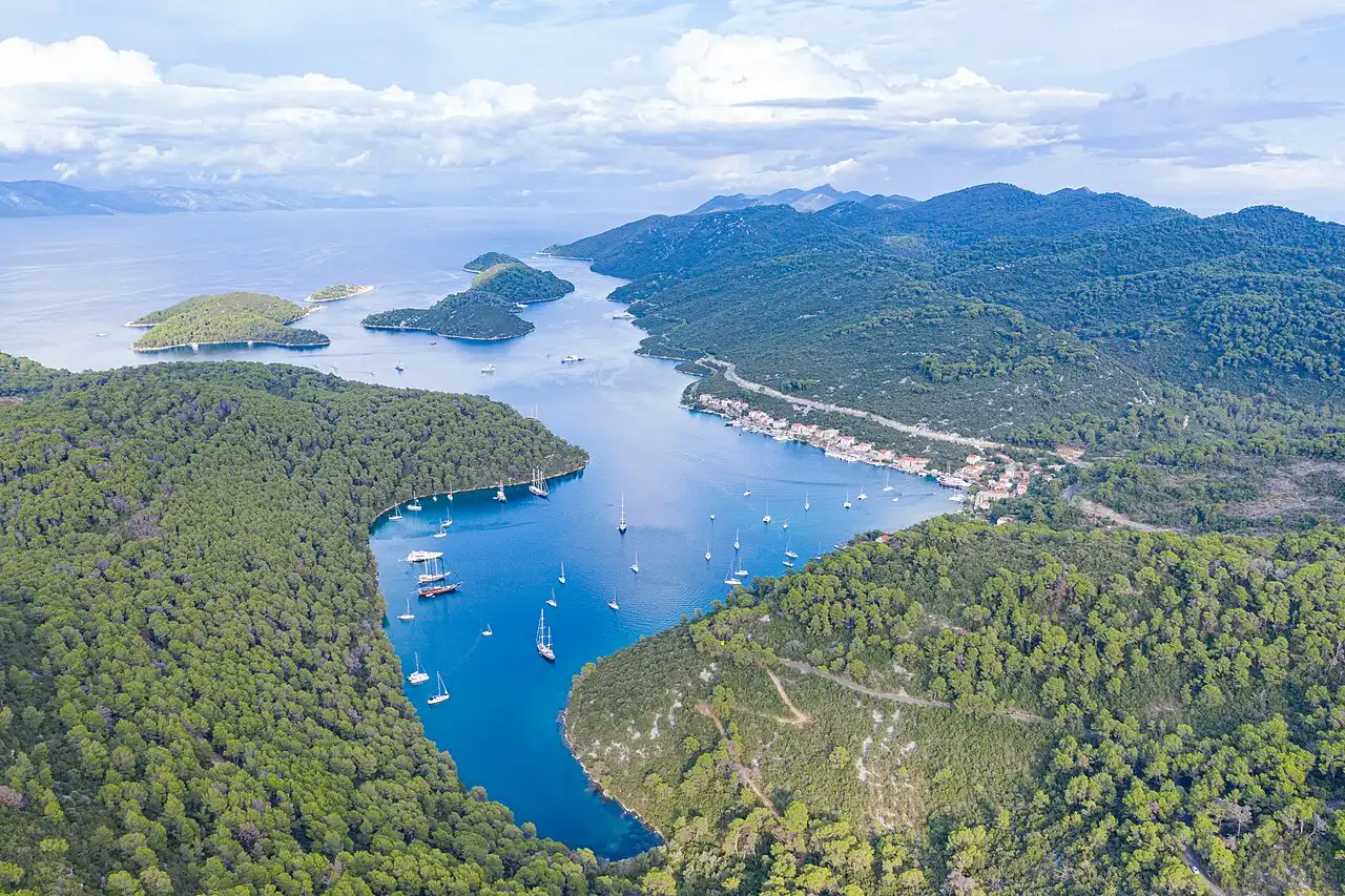 Aerial view of the sheltered natural harbour and marina of Polače on Mljet, with yachts moored and wooded hills around