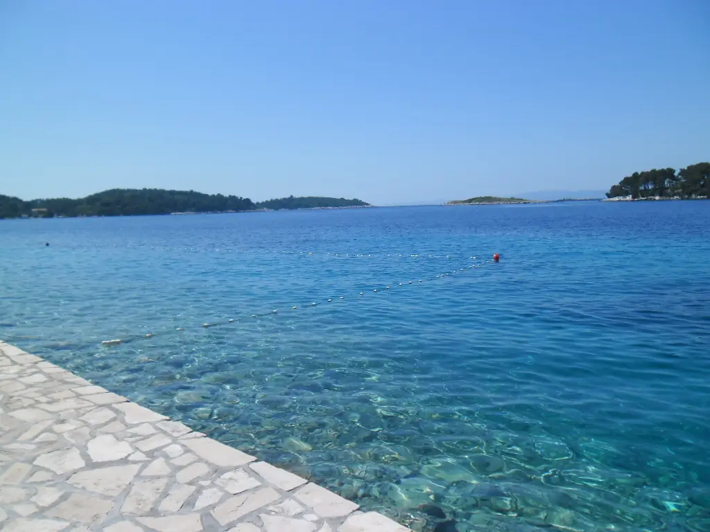 The waterfront of Pomena on Mljet, with small boats moored and Hotel Odisej along the bay