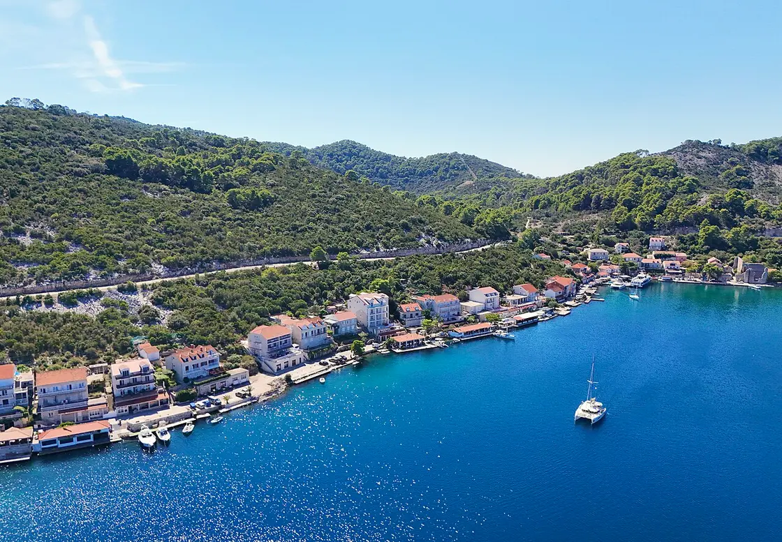The sheltered natural harbour of Polače on Mljet with boats moored and wooded hills behind