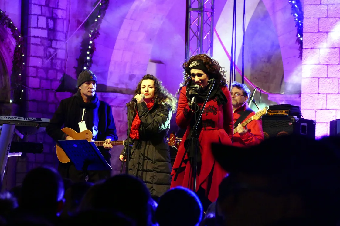 Two singers in red coats on a stage lit in purple at a New Year's Eve concert in Dubrovnik