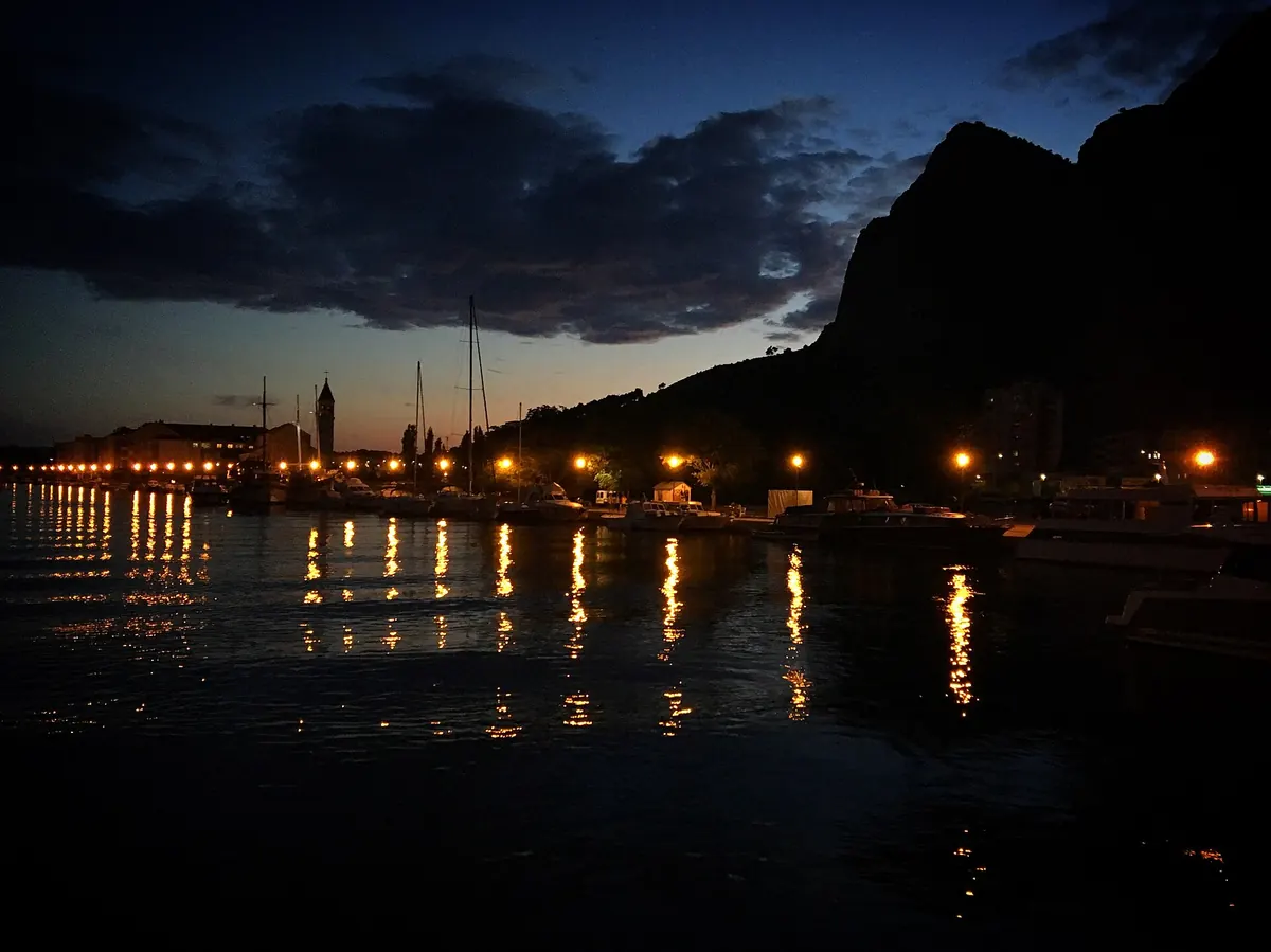 Omiš lights reflected in the Cetina at night with the canyon wall behind