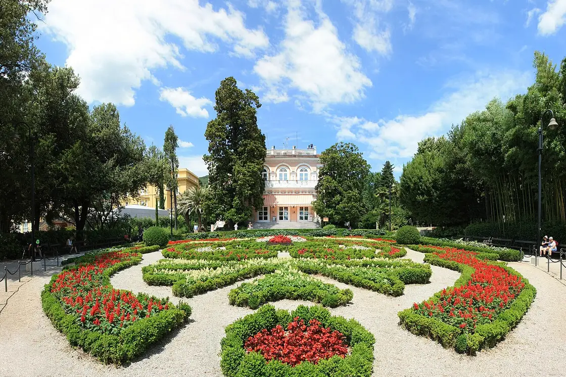 Villa Angiolina with manicured lawns and tall trees in Angiolina Park
