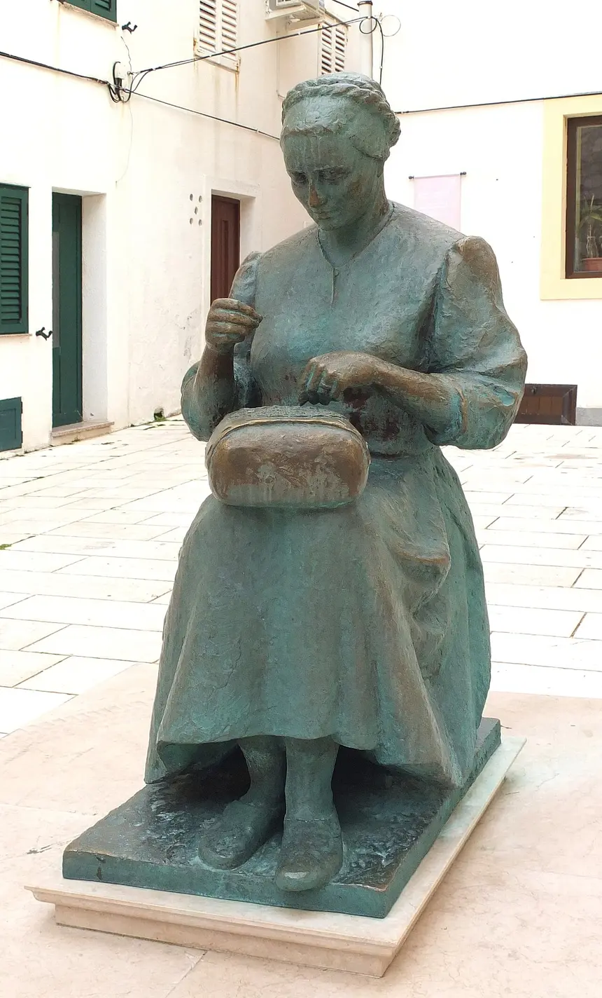 A lacemaker in Pag working a piece of white Pag lace on a round cushion
