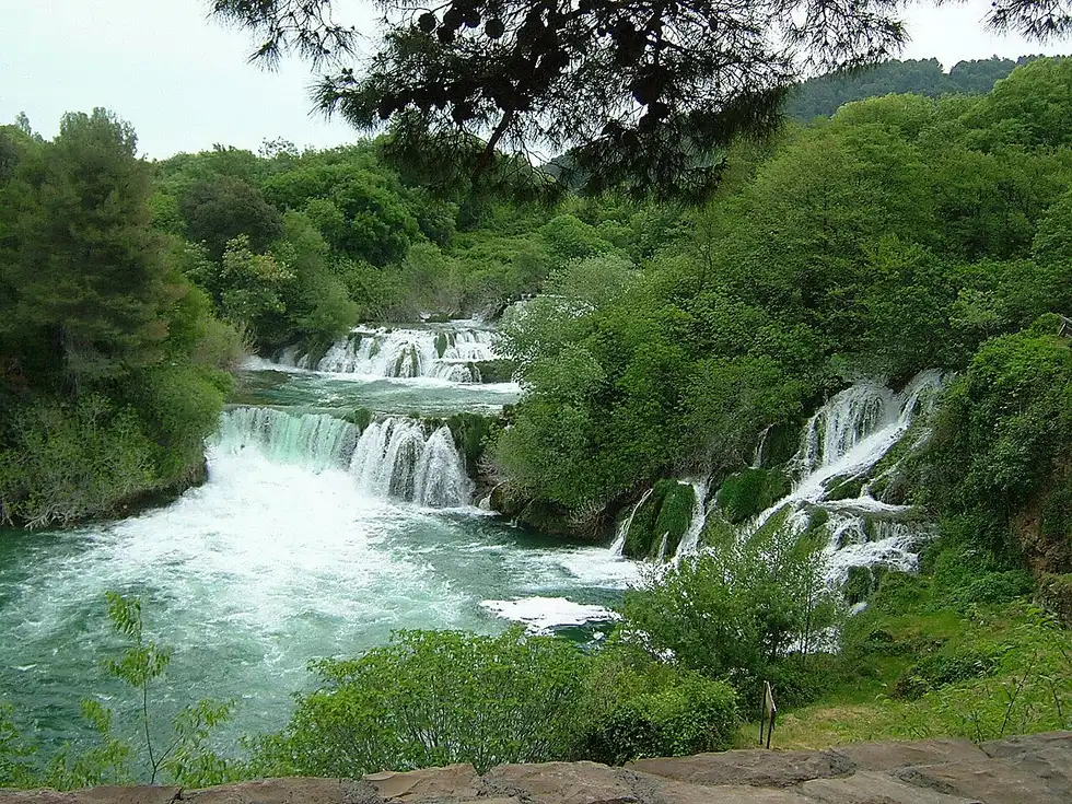 The wide Skradinski Buk cascades spilling through green forest at Krka