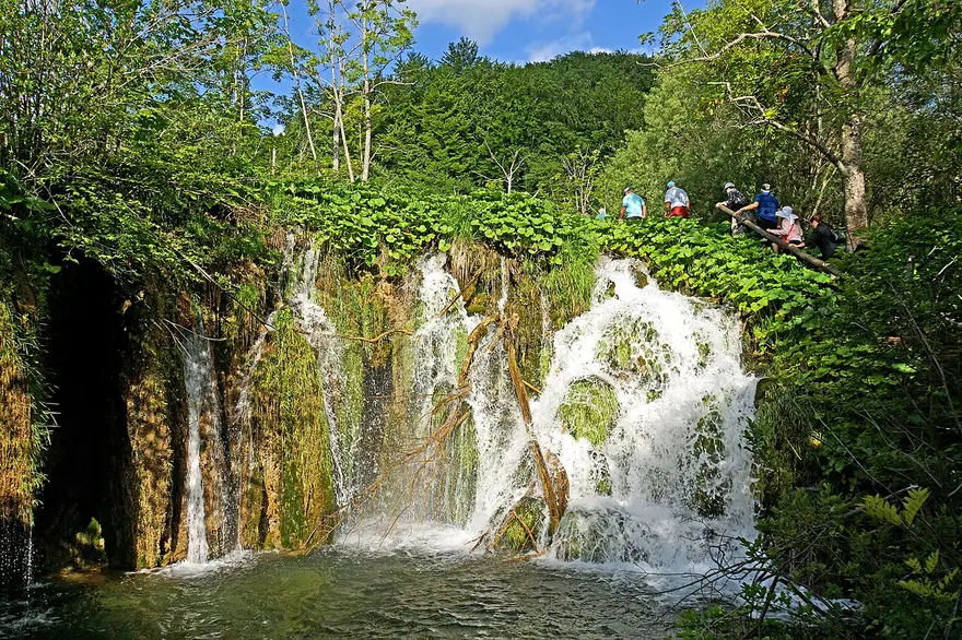 A wide travertine waterfall in the Lower Lakes with visitors above it