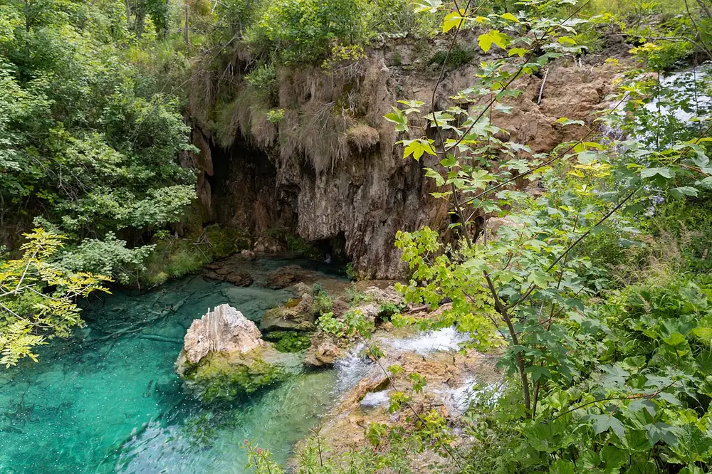 Crystal-clear turquoise water over travertine rock at a Plitvice spring