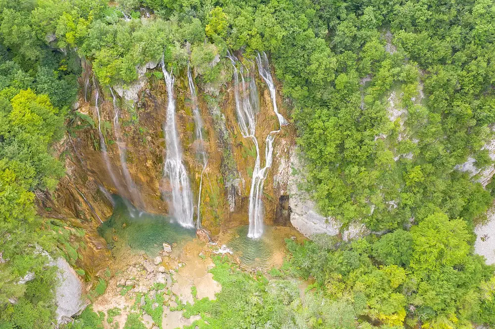 Aerial view of a wide multi-strand waterfall over travertine at Plitvice