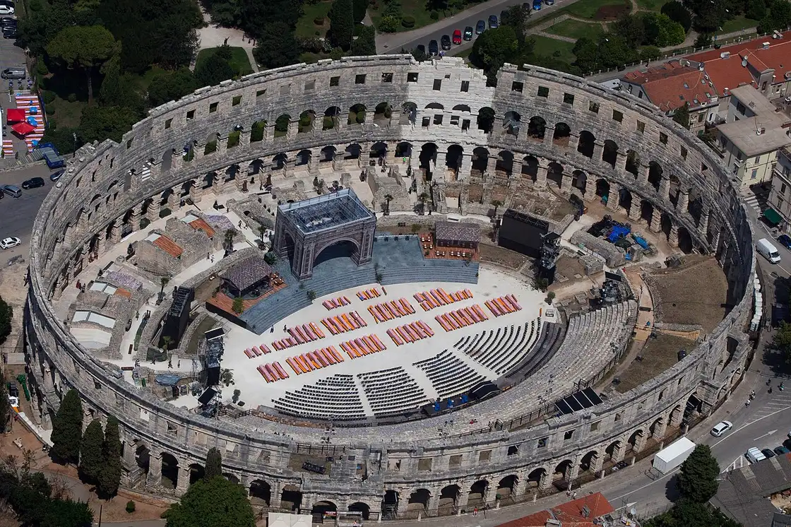 Aerial view of the Pula Arena with a stage and rows of seating set up on the floor for a summer concert