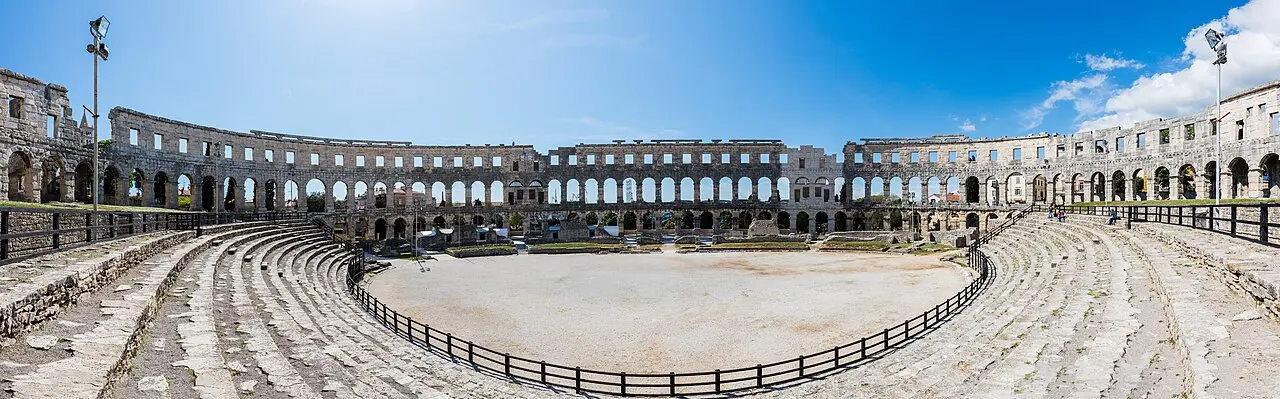 Panoramic view inside the Pula Arena, showing the full elliptical wall and tiers of arches from the arena floor