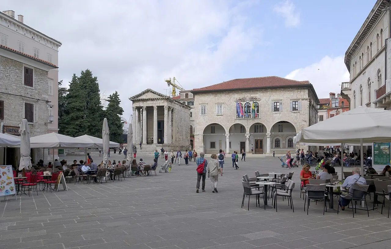 The Forum square in Pula with café terraces, the columned Temple of Augustus and the arcaded town hall