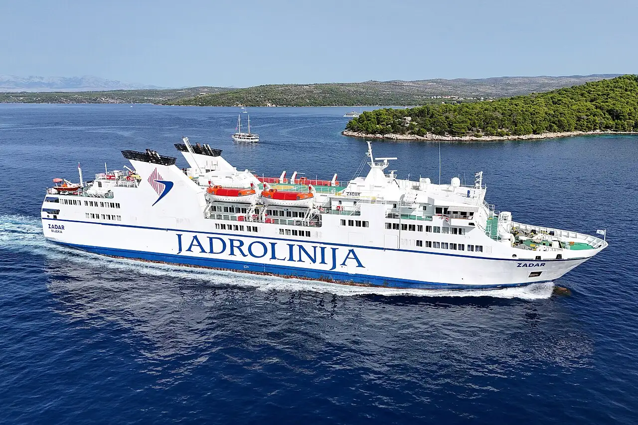 A blue-and-white Jadrolinija car ferry crossing the Adriatic toward a Croatian island