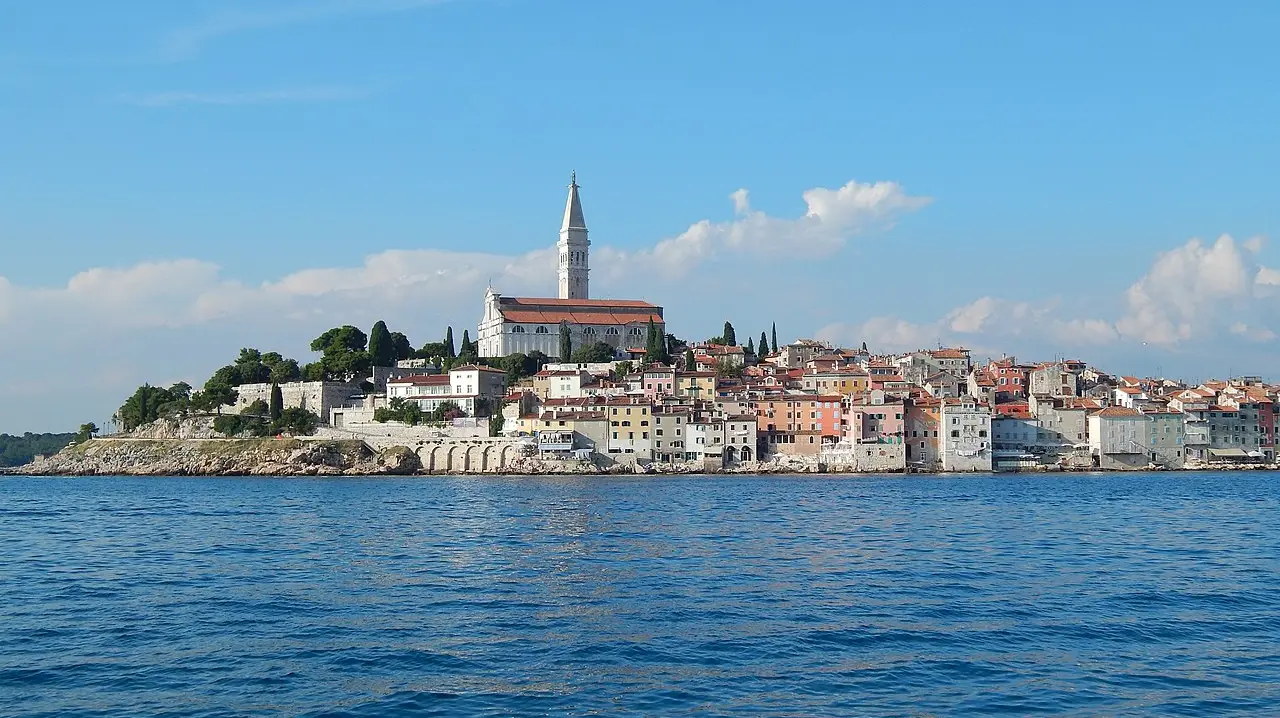 The old town of Rovinj on its peninsula, with the bell tower of St Euphemia rising over the houses, seen from the sea