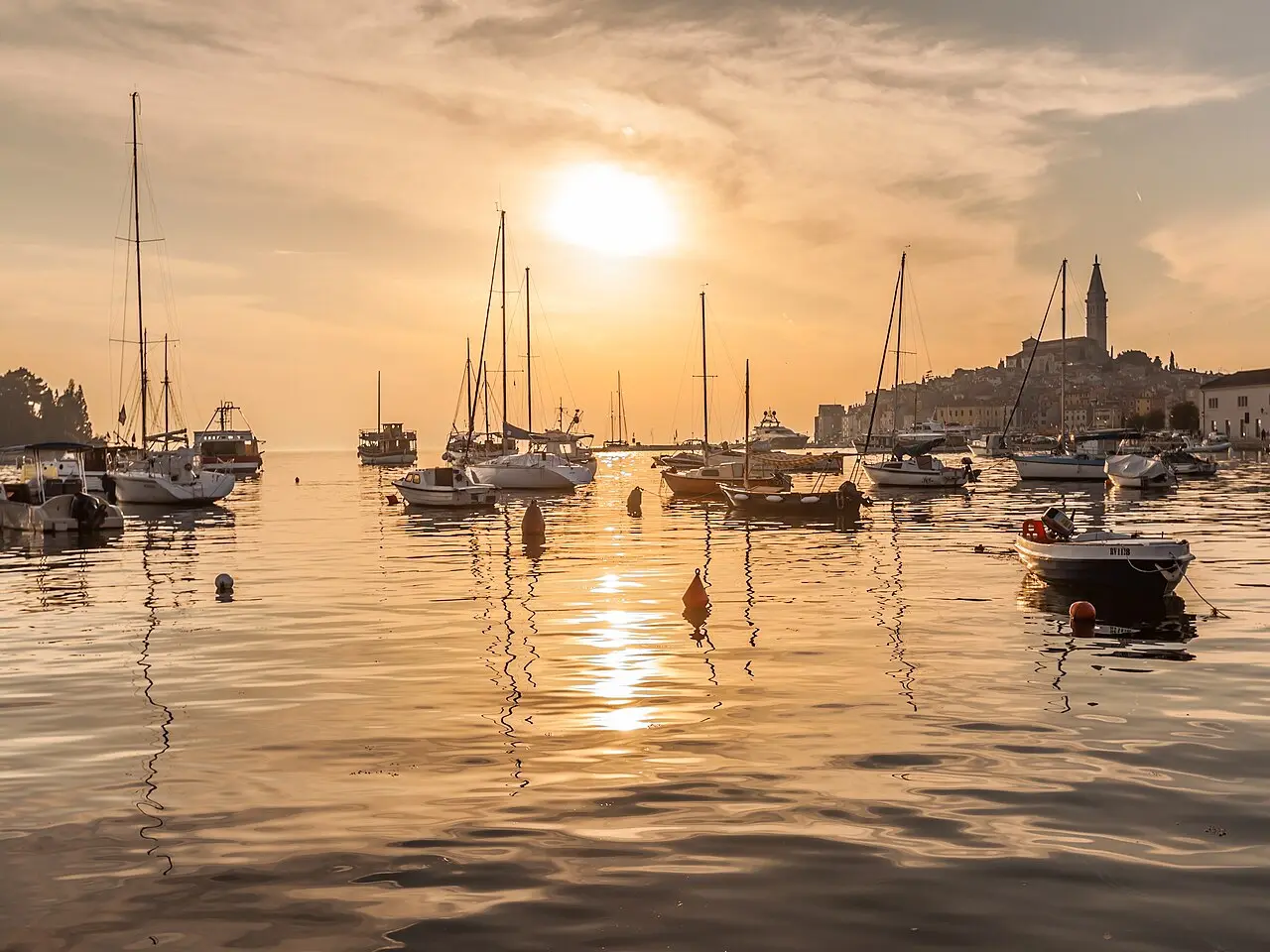 The skyline of Rovinj glowing at sunset, with the St Euphemia bell tower silhouetted