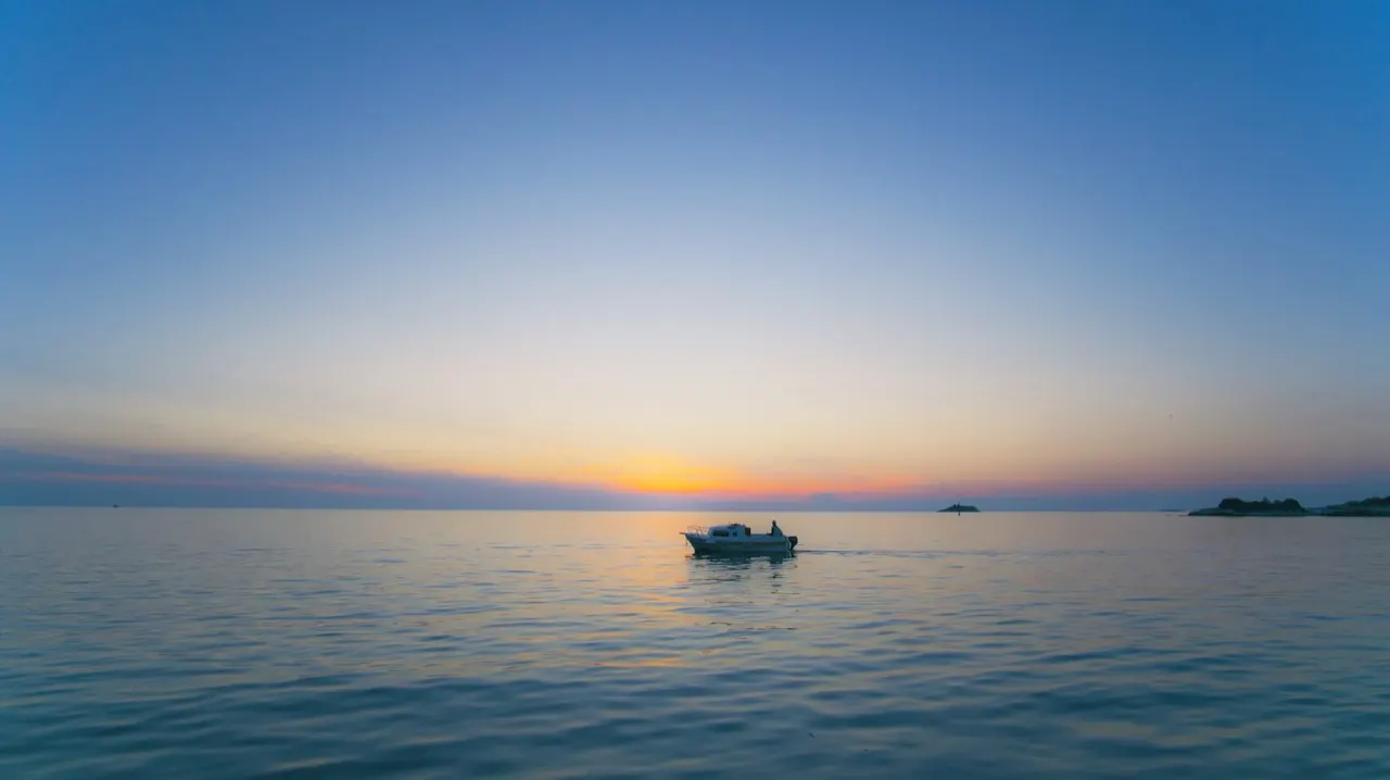 A small yacht sailing alone on open Adriatic water under a pale sky