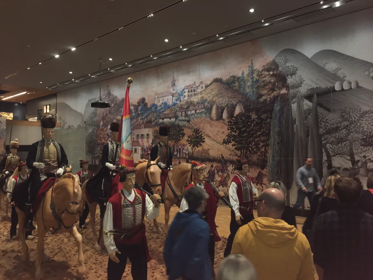 Life-size figures of Alka riders on horseback and squires on foot inside the Museum of the Sinj Alka, in front of a painted panorama of Sinj