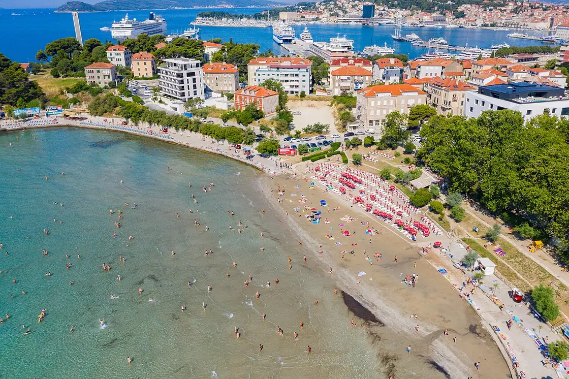 Aerial view of Bačvice beach in Split with its sandy bay, beach-bar umbrellas and the harbour behind