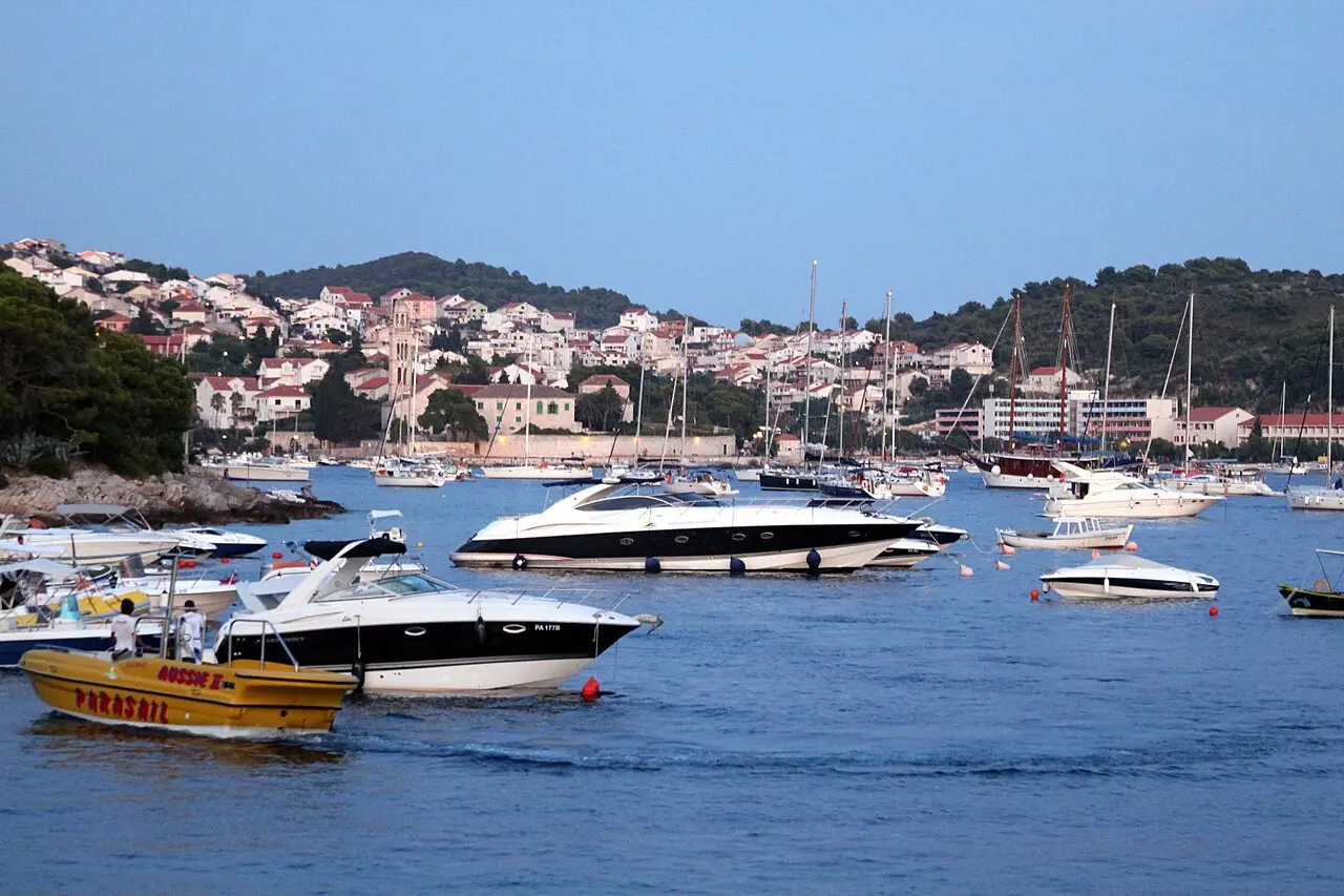 Hvar Town harbour with moored yachts and the old town climbing the hillside