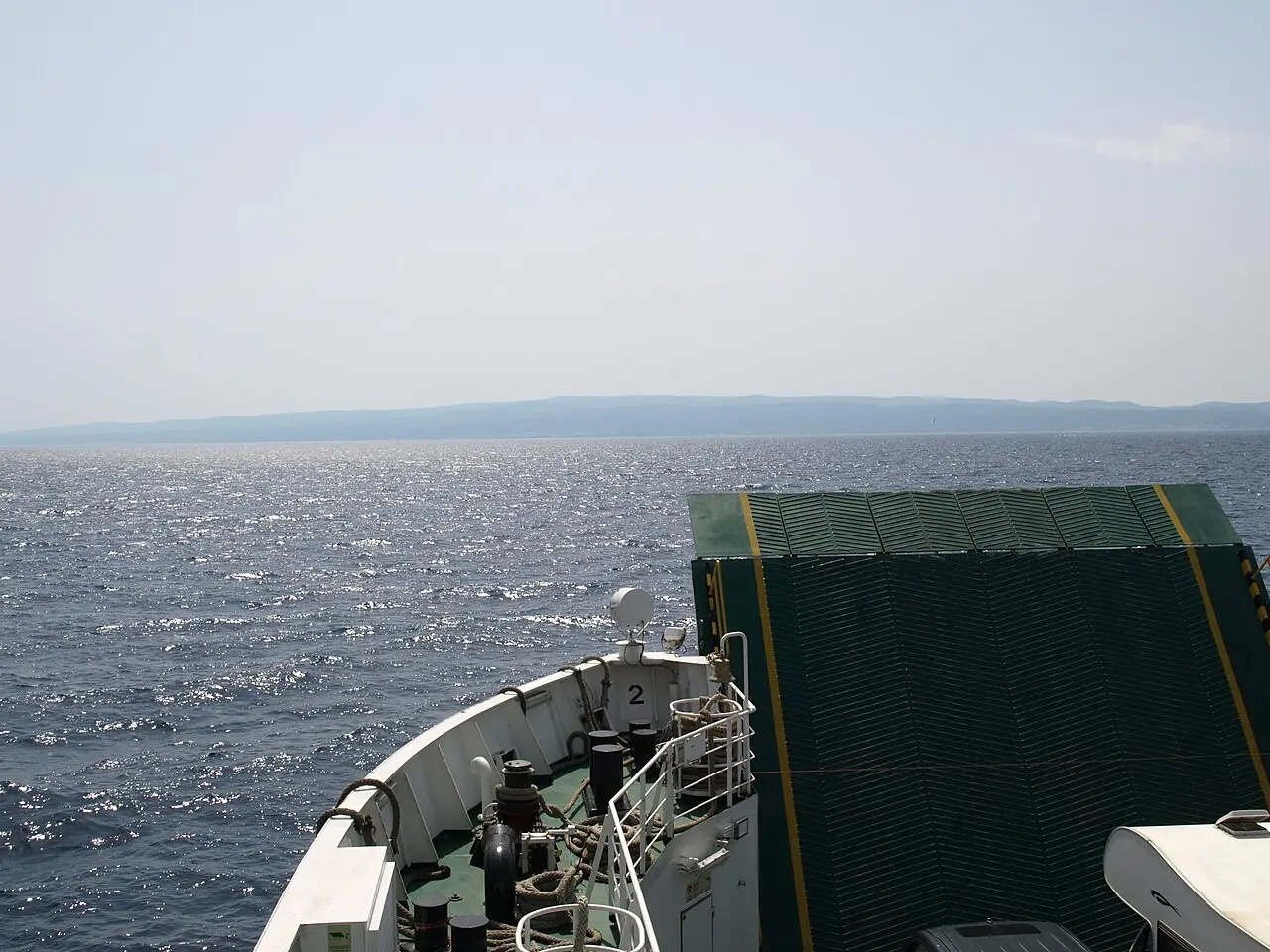 The bow of a Croatian car ferry crossing open water toward an island