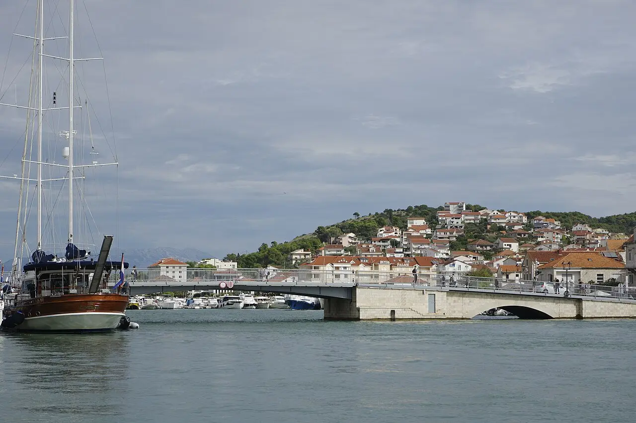 The bridge across the Trogir canal connecting the old town island to Čiovo, with boats and houses on the hillside
