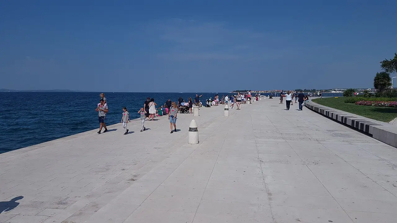 The waterfront promenade in Zadar at dusk with people walking along the sea