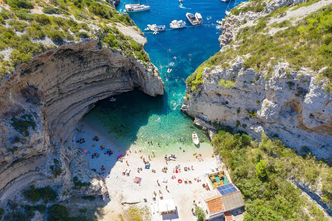 Aerial view of Stiniva cove on Vis, a pebble beach enclosed by high cliffs with a narrow sea gap