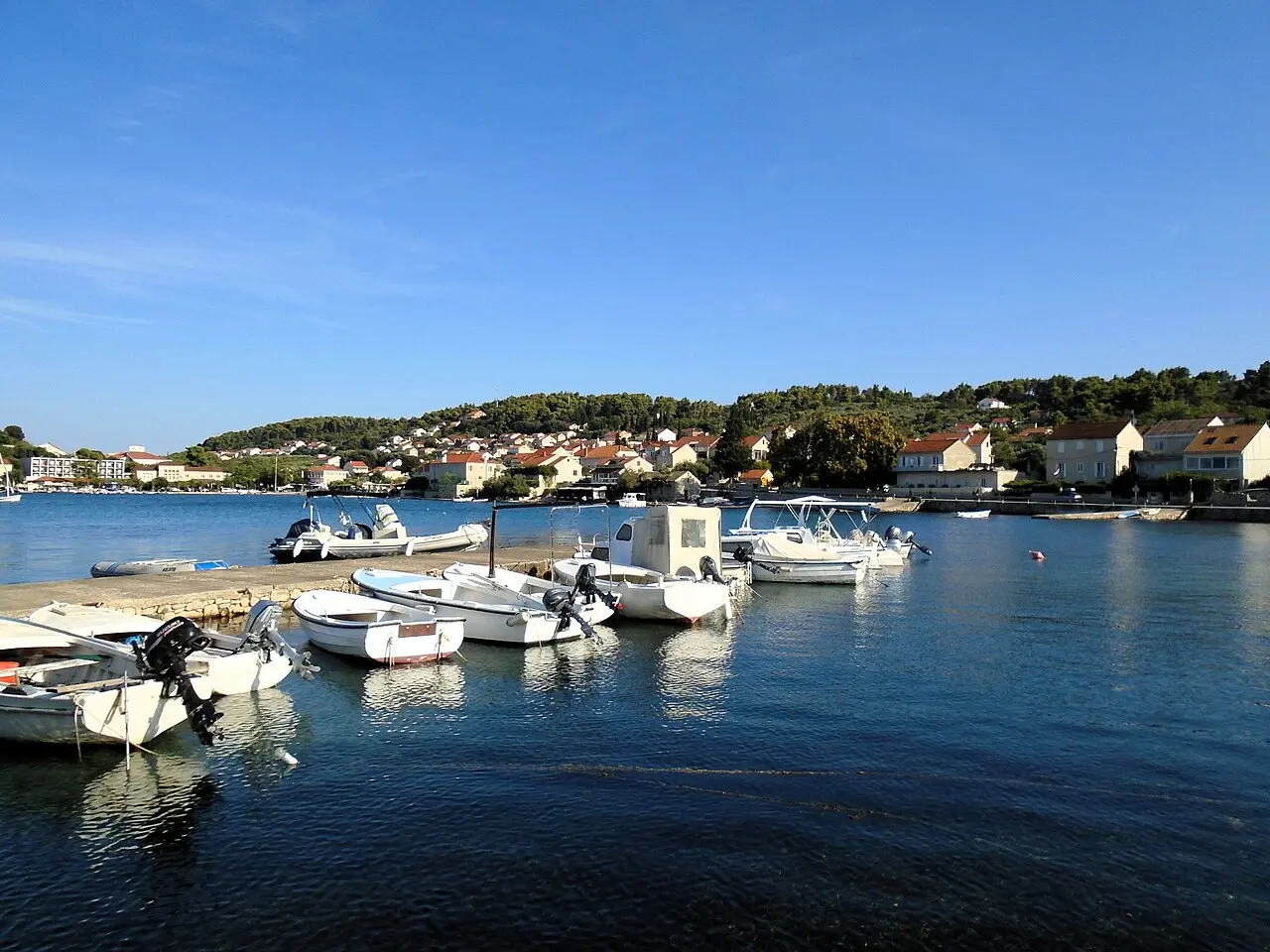 The small harbour at Lumbarda with boats and stone houses along the water