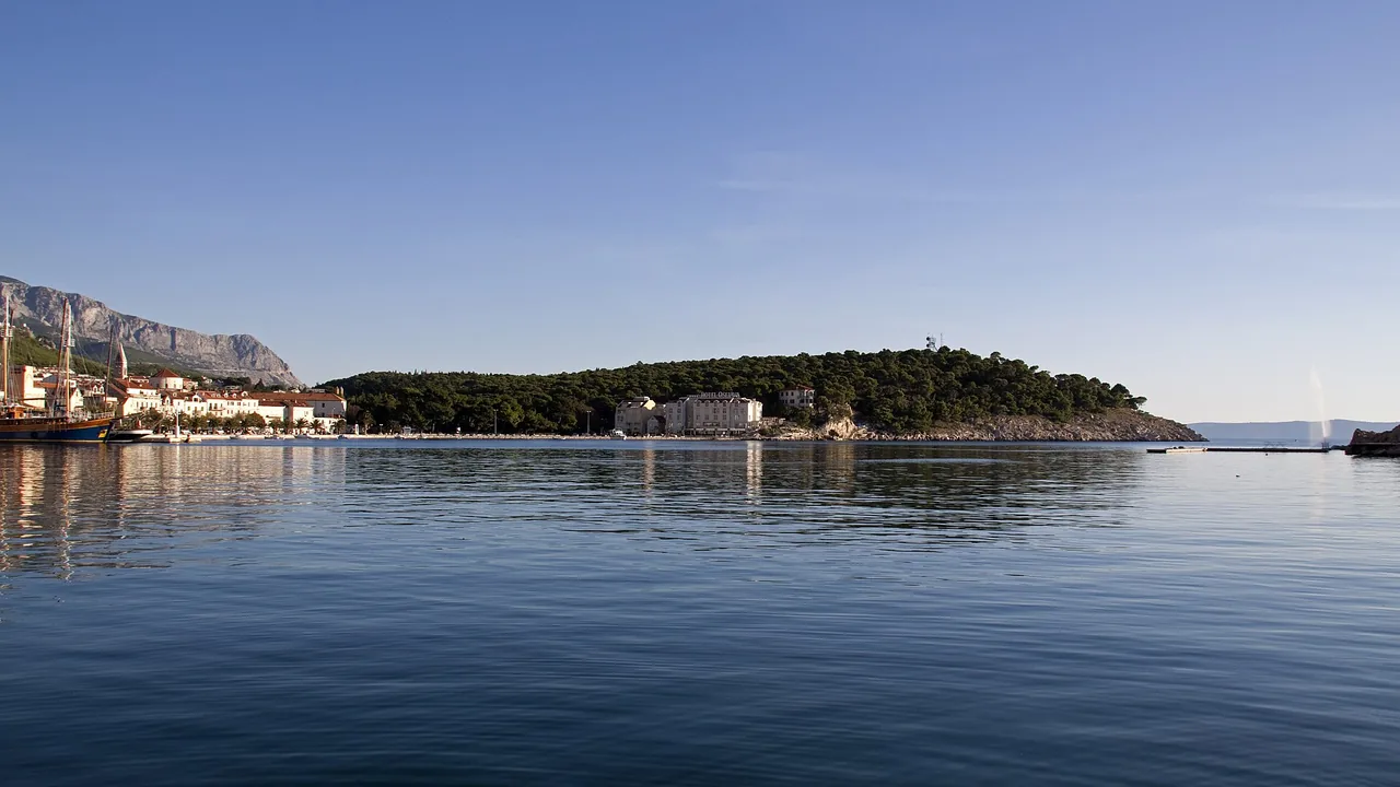 Palm-lined harbour of Makarska with boats at the quay and Biokovo rising behind the town