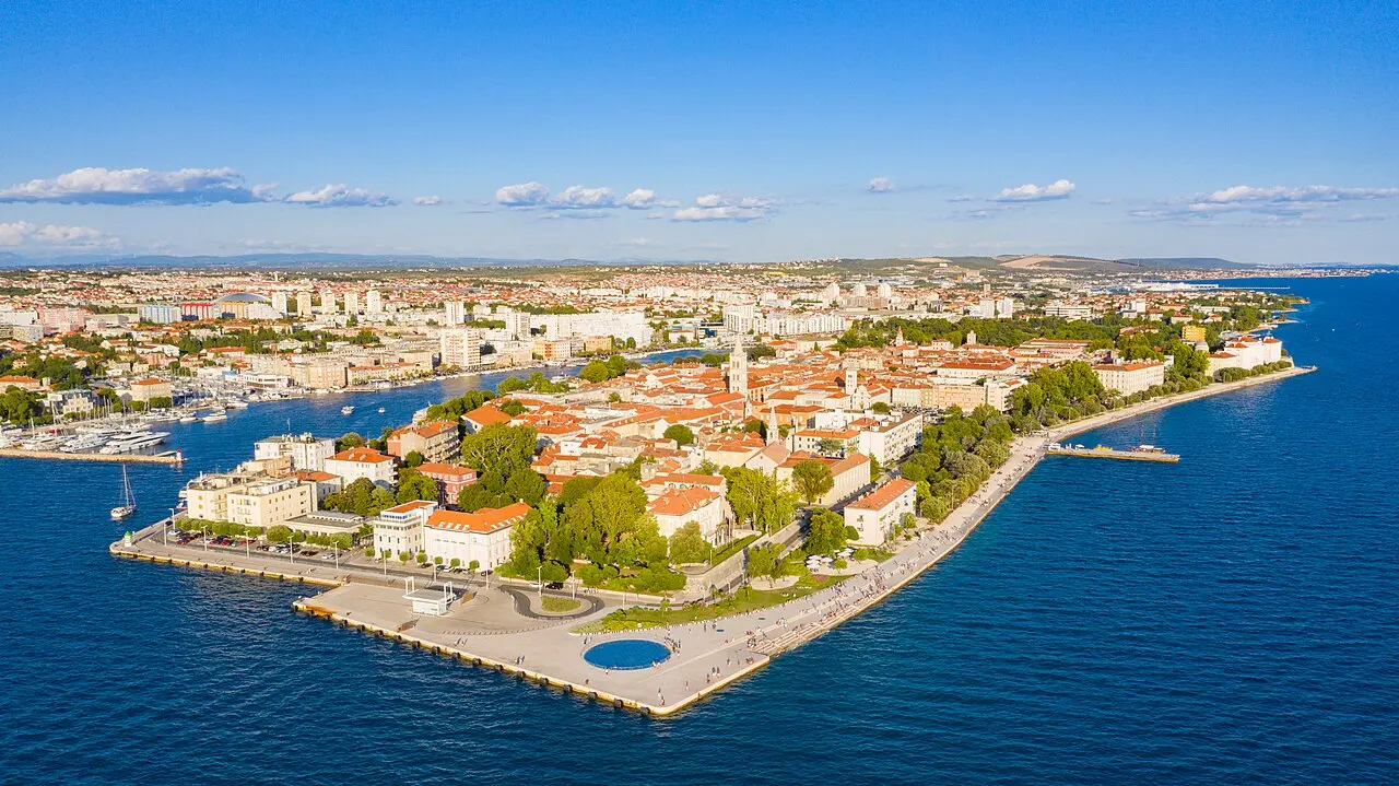Aerial view of the tip of Zadar old town at dusk with the round Greeting to the Sun and the Sea Organ steps meeting the Adriatic