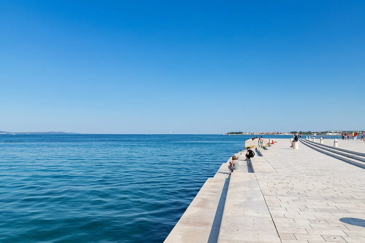 Wide marble steps of the Zadar Sea Organ descending into the sea, with people sitting along them