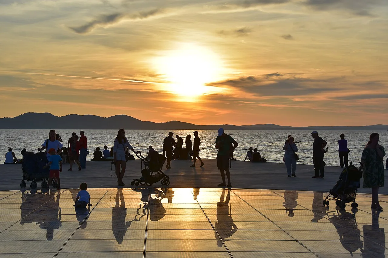 The sun setting over the Adriatic and distant islands seen from the Zadar waterfront, sky in orange and pink