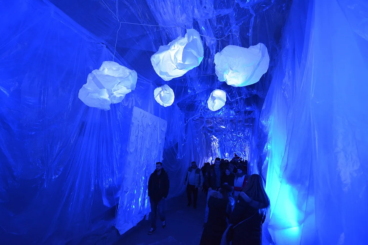 Visitors walking under glowing white sculptures and blue lighting inside the Gric Tunnel in Zagreb during Advent