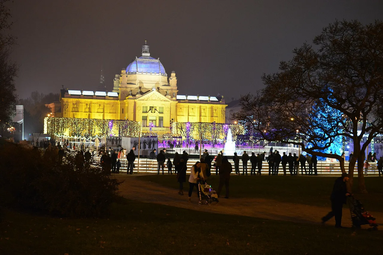 Skaters on the illuminated Ledeni park ice rink in front of the floodlit Art Pavilion in Zagreb at night