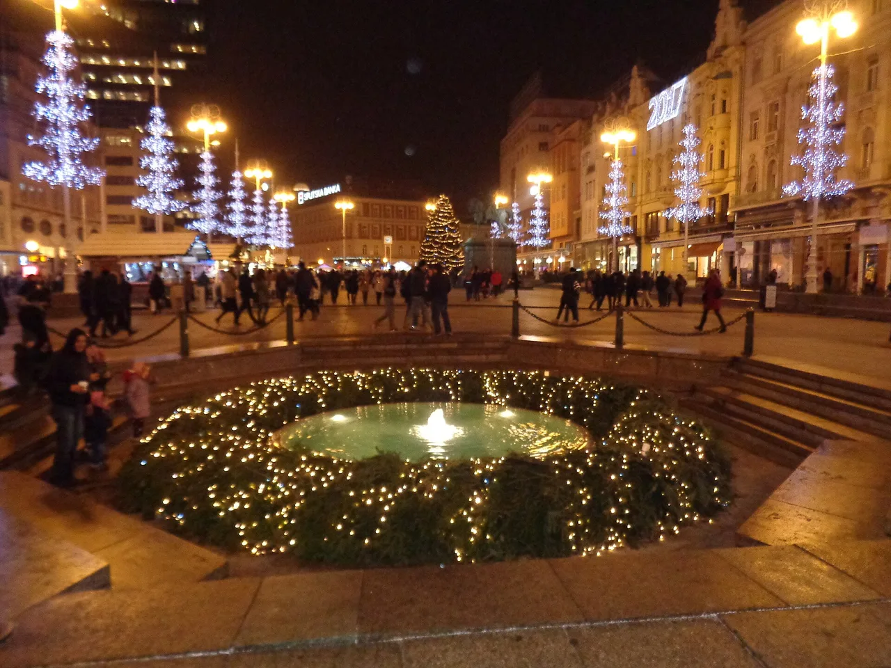 The Manduševac fountain on Ban Jelacic Square edged with fairy lights, with the Christmas tree behind it
