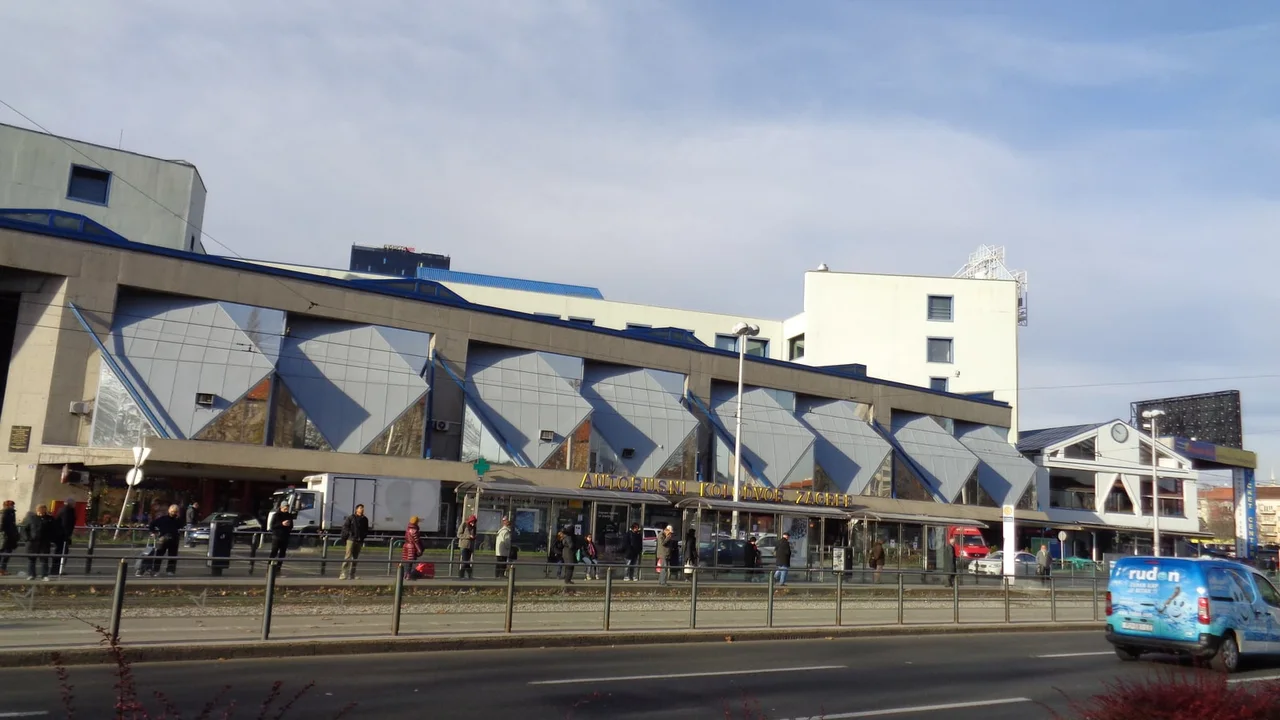 The Zagreb Main Bus Station, a long facade of diamond-shaped glass panels with the station name above the stop shelters and a tram line in front