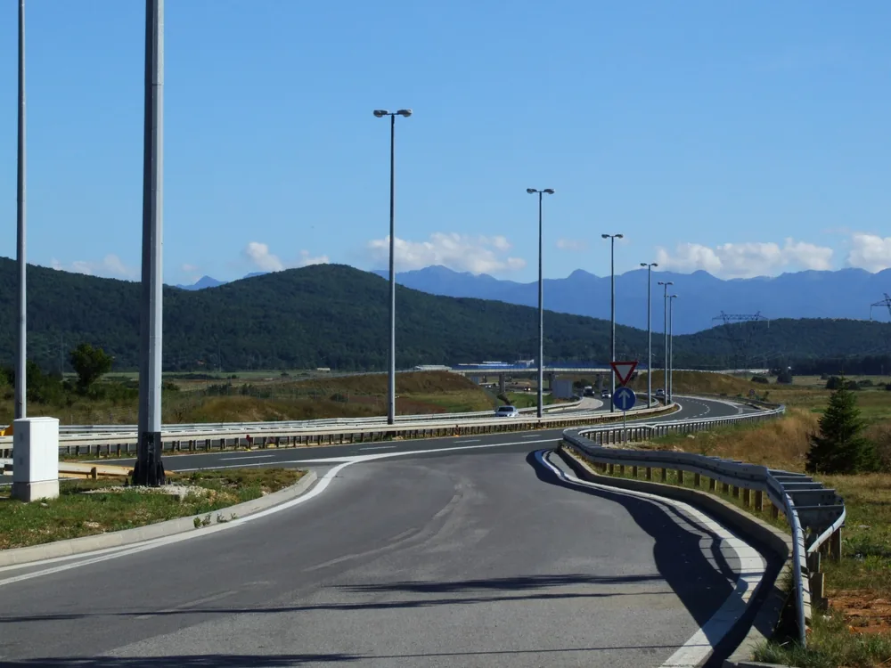 A slip road joining the A1 motorway in Lika with wooded hills and a mountain range behind