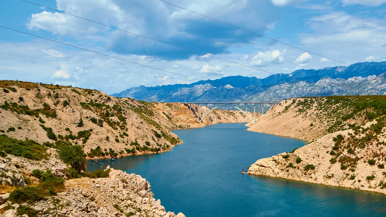 The A1 motorway bridge arching over the Novsko Zdrilo channel with the Velebit mountains behind